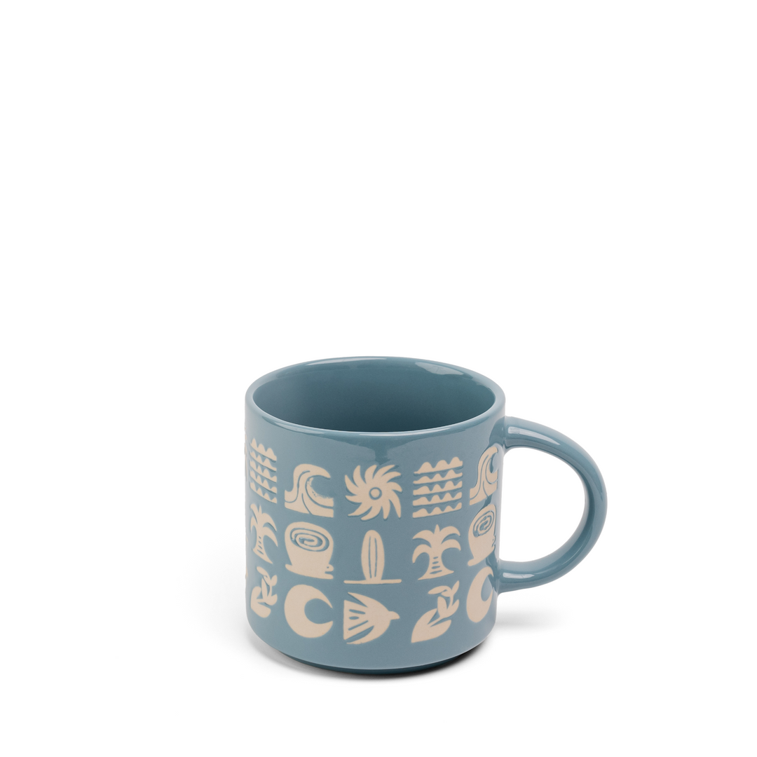 A dusty blue ceramic mug with a handle, decorated with a cream-colored pattern of stylized suns, waves, and abstract symbols, shown on a plain white background.