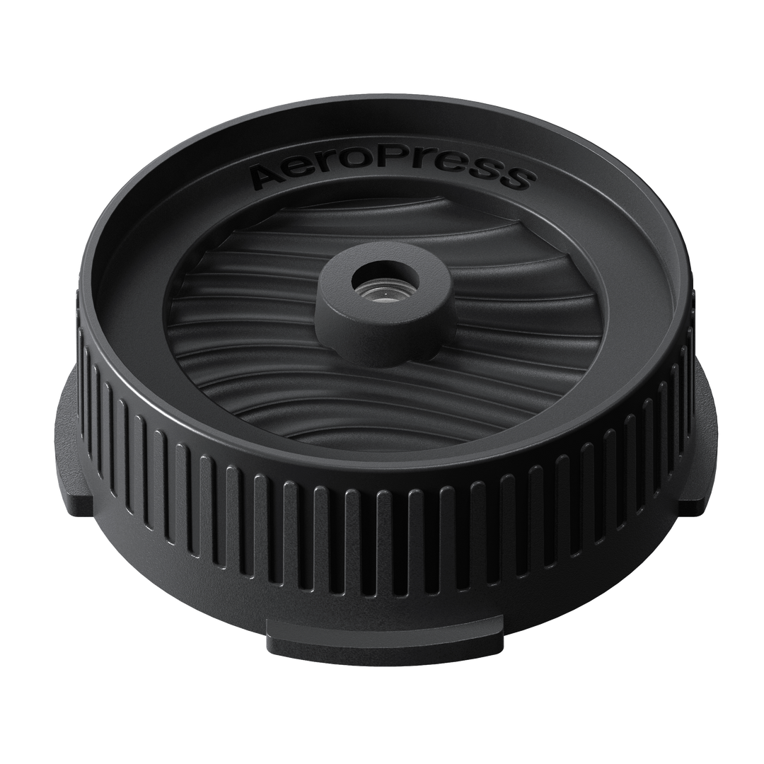Black AeroPress coffee brewing component on a white background