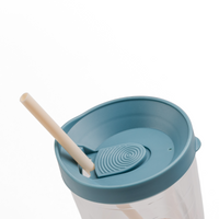 Close-up of a clear plastic tumbler with a muted blue lid and straw on a white background.