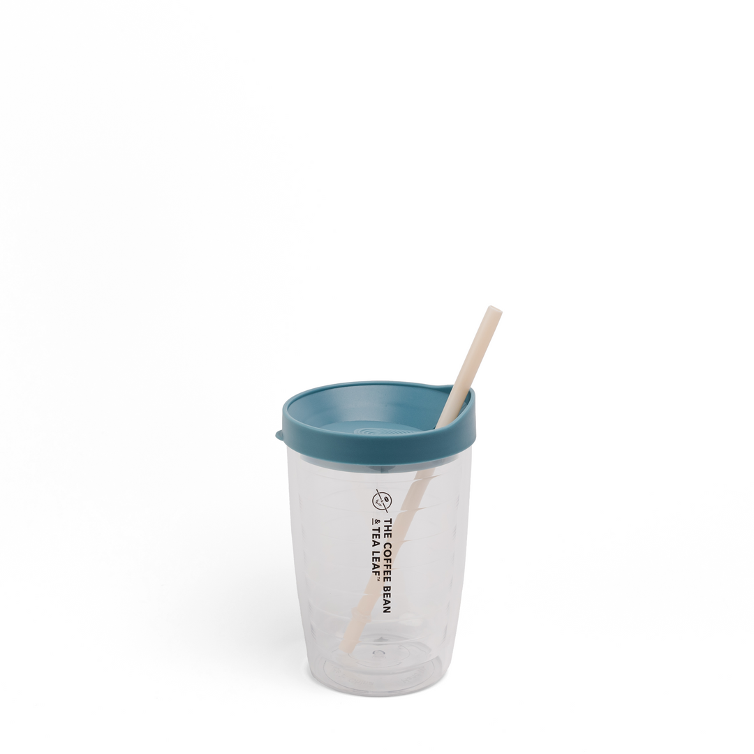 A clear plastic travel tumbler with a teal lid and a light wood straw, featuring the text 'THE COFFEE BEAN TEA SHOP' printed vertically on the front, set against a plain white background.