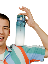 A smiling young man in a striped shirt holds up a translucent water bottle with a blue-to-white gradient design against a solid white background.