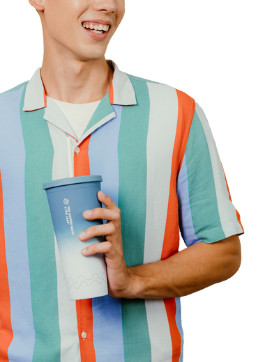 A man wearing a short-sleeve button-up shirt with vertical stripes in teal, orange, light blue, white, and lavender, holding a blue-to-white gradient travel tumbler cup.