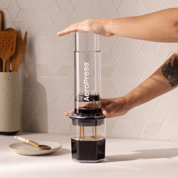 Person using an Aeropress XL coffee press on a kitchen counter.