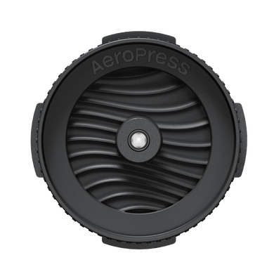 Black AeroPress coffee brewing component on a white background