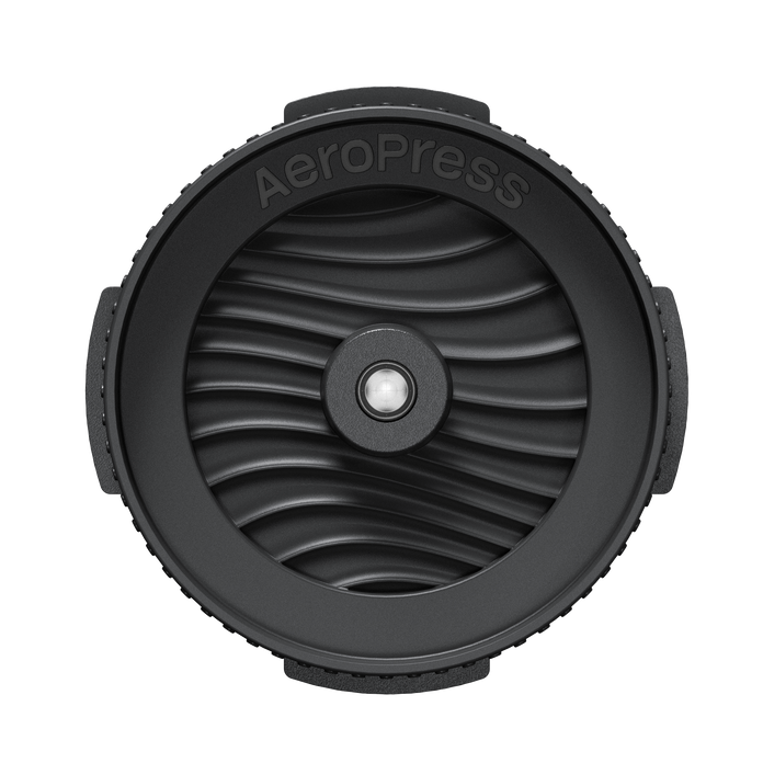 Black AeroPress coffee brewing component on a white background