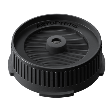 Black AeroPress coffee brewing component on a white background