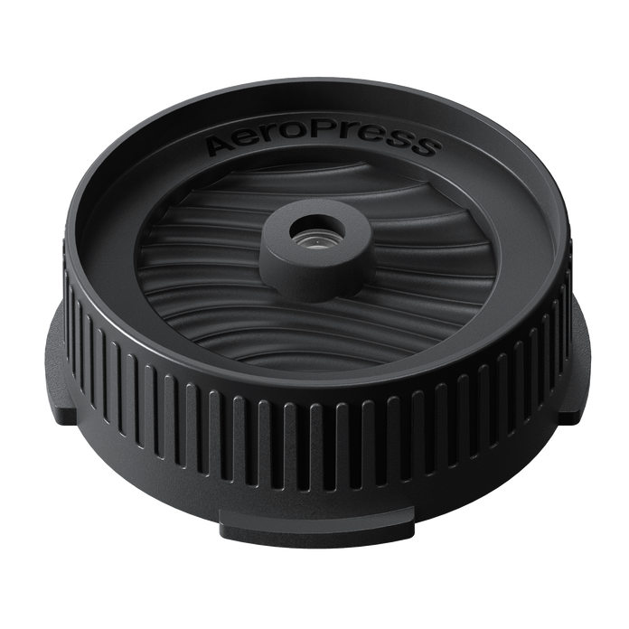 Black AeroPress coffee brewing component on a white background