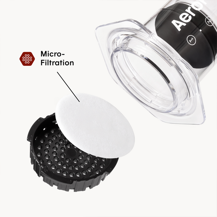 Aeropress coffee maker with a focus on micro-filtration component on a white background