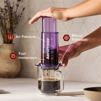 Person using an Aeropress coffee maker with labeled features on a kitchen counter.