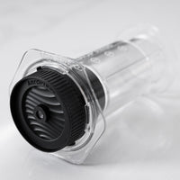 Clear AeroPress coffee brewing device with black AeroPress cap on a light gray background