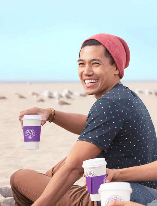 Man on beach holding coffee